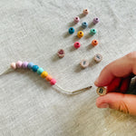 Child threading beads onto elastic cord, creating a "BFF" friendship bracelet.