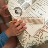 Child using cross-stitched wooden bookmark in a book