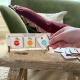 Child's and placing "calm" token on a wooden feelings chart next to "excited" and "proud."