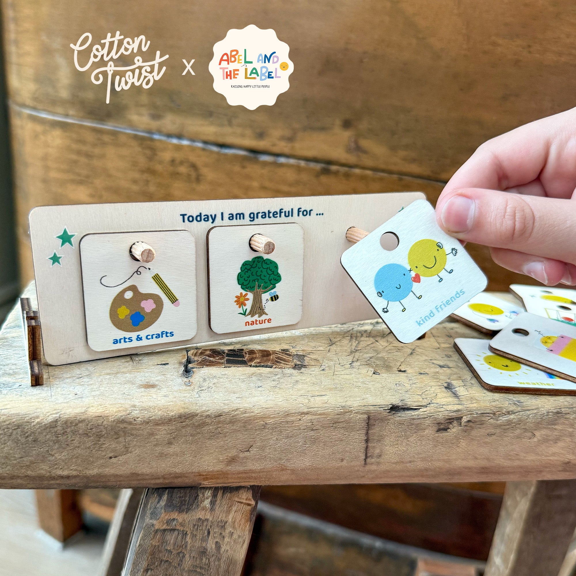 Child selecting a wooden gratitude token to place on a “Today I am grateful for…” chart with colourful illustrations.