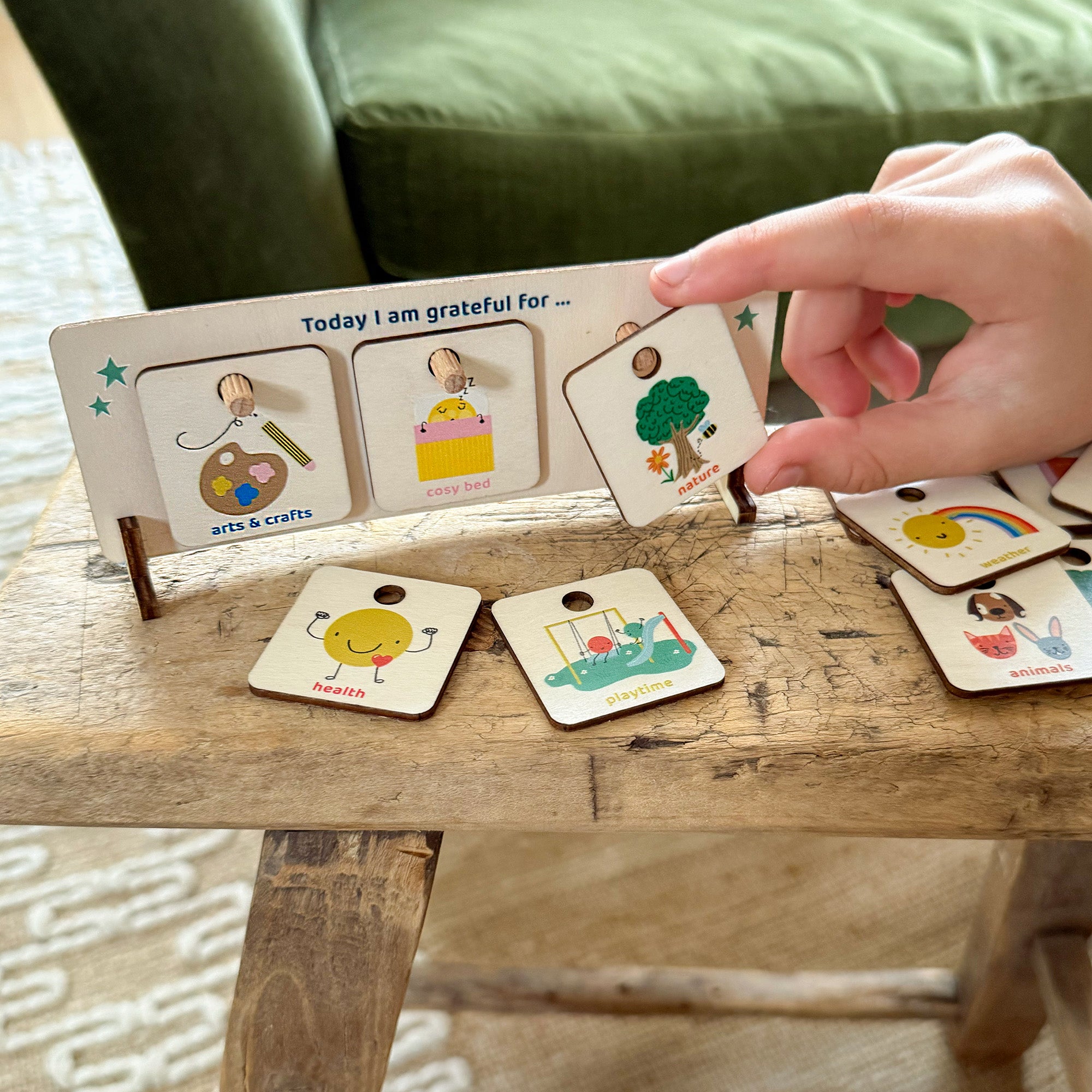Child selecting a wooden gratitude token to place on a “Today I am grateful for…” chart with colourful illustrations.