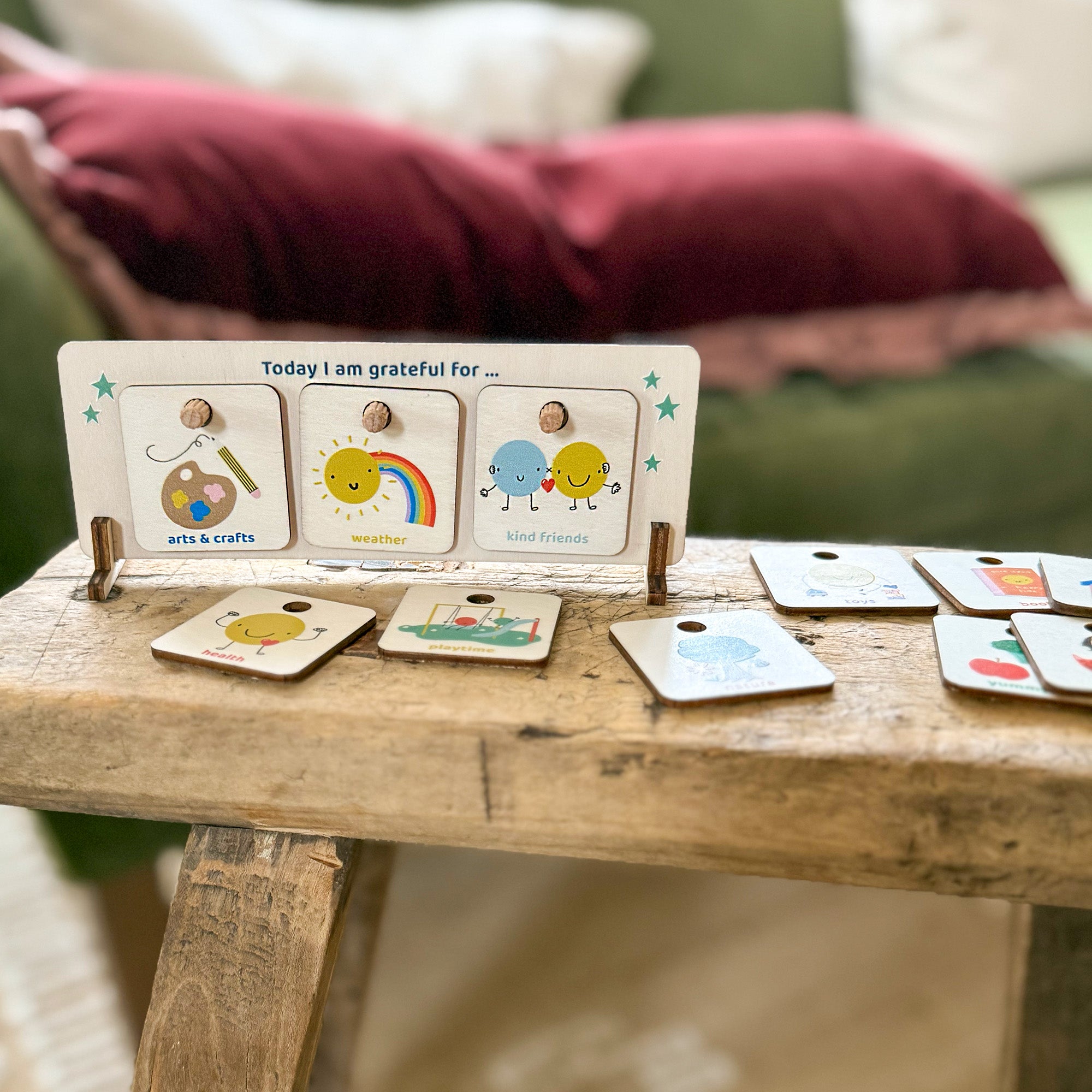 Wooden gratitude chart with three tokens slotted in and additional illustrated tokens displayed around it.