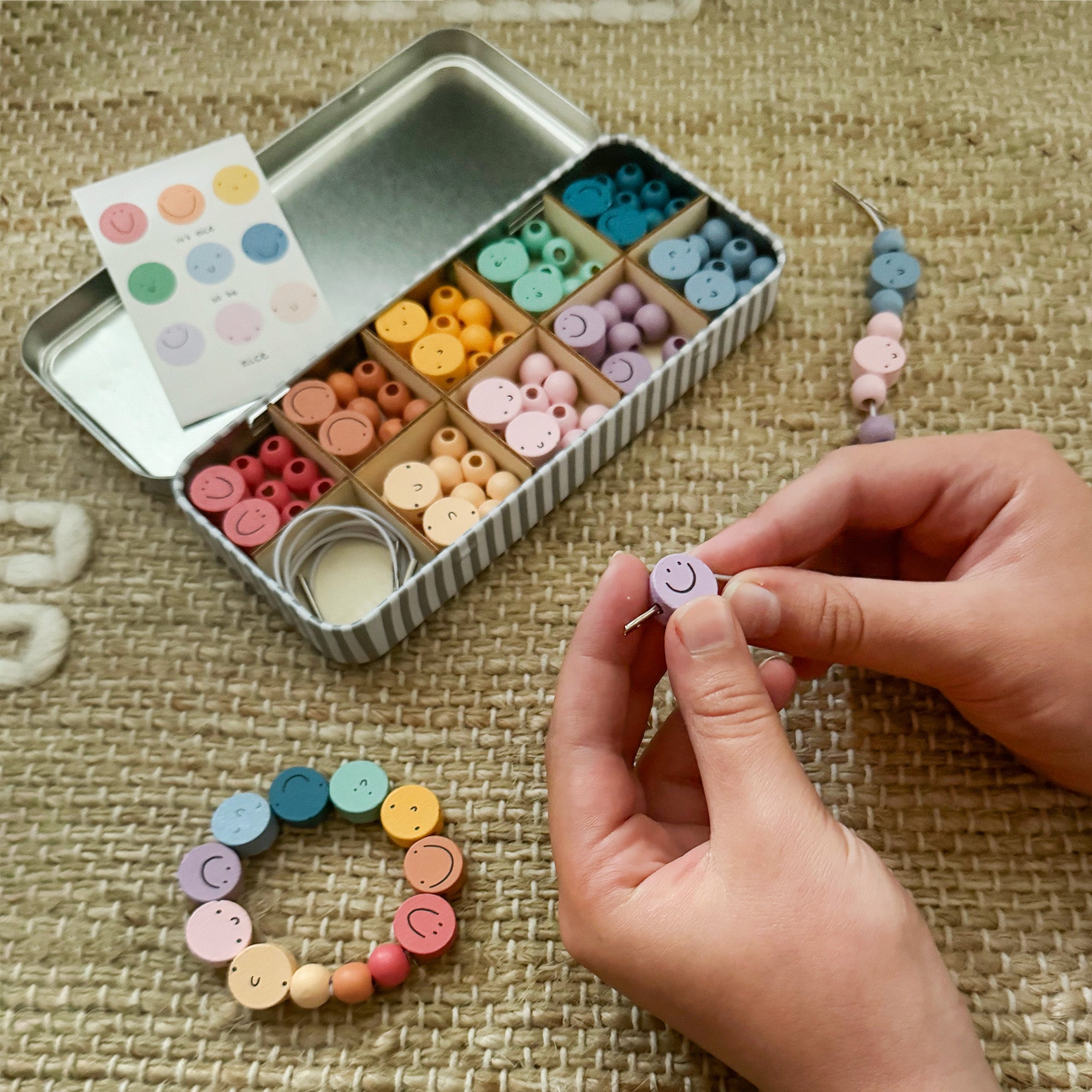 "It's Nice To Be Nice" bracelet beading kit displayed with colourful wooden beads and smiley face charms.