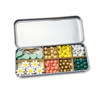 Open daisy beading kit displaying wooden daisy, leaf, and spherical beads, elastic cords