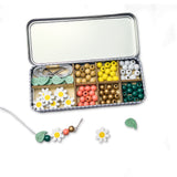 Open daisy beading kit displaying wooden daisy, leaf, and spherical beads, elastic cords