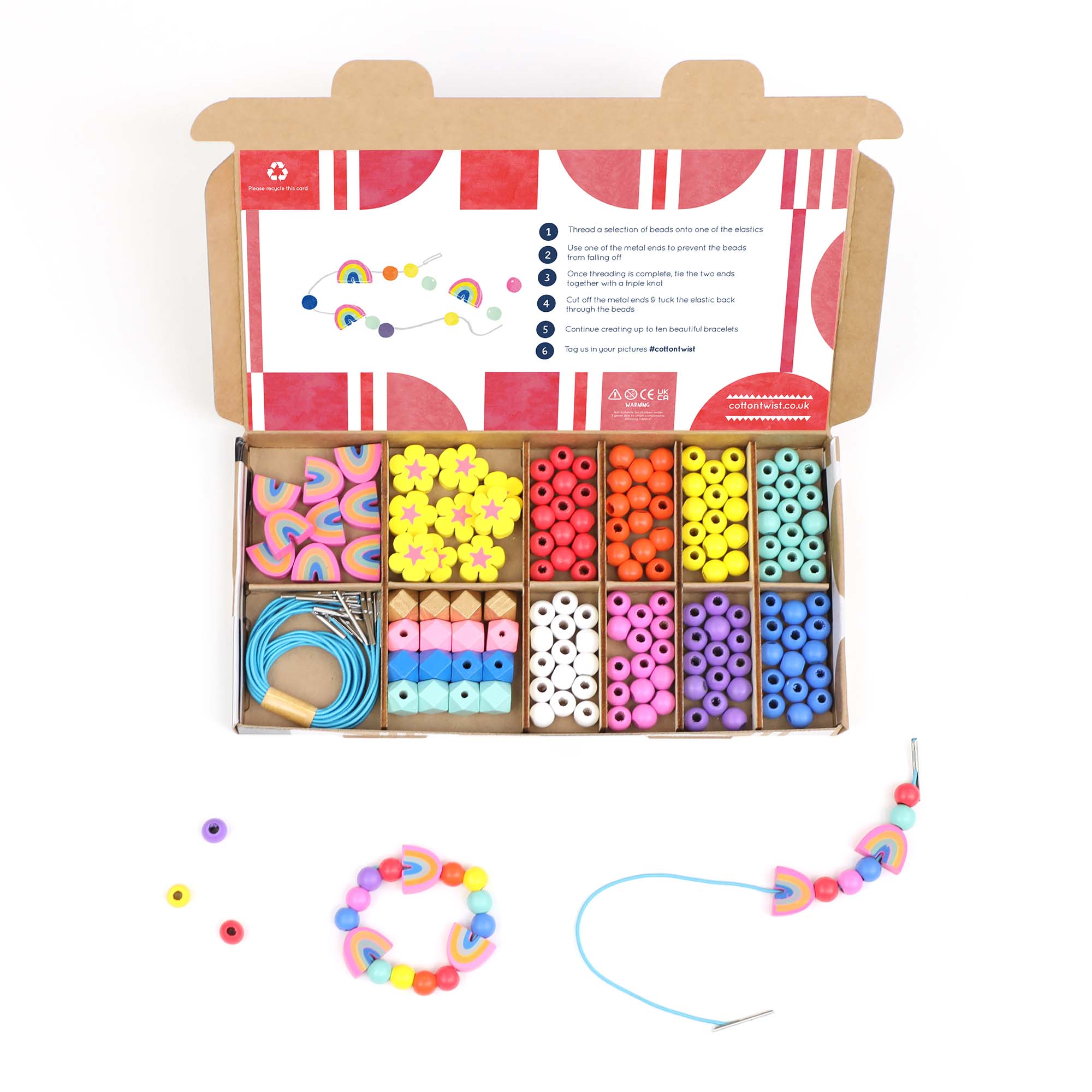 Open beading kit with rainbow and flower beads, alongside two sample bracelets on a white background.