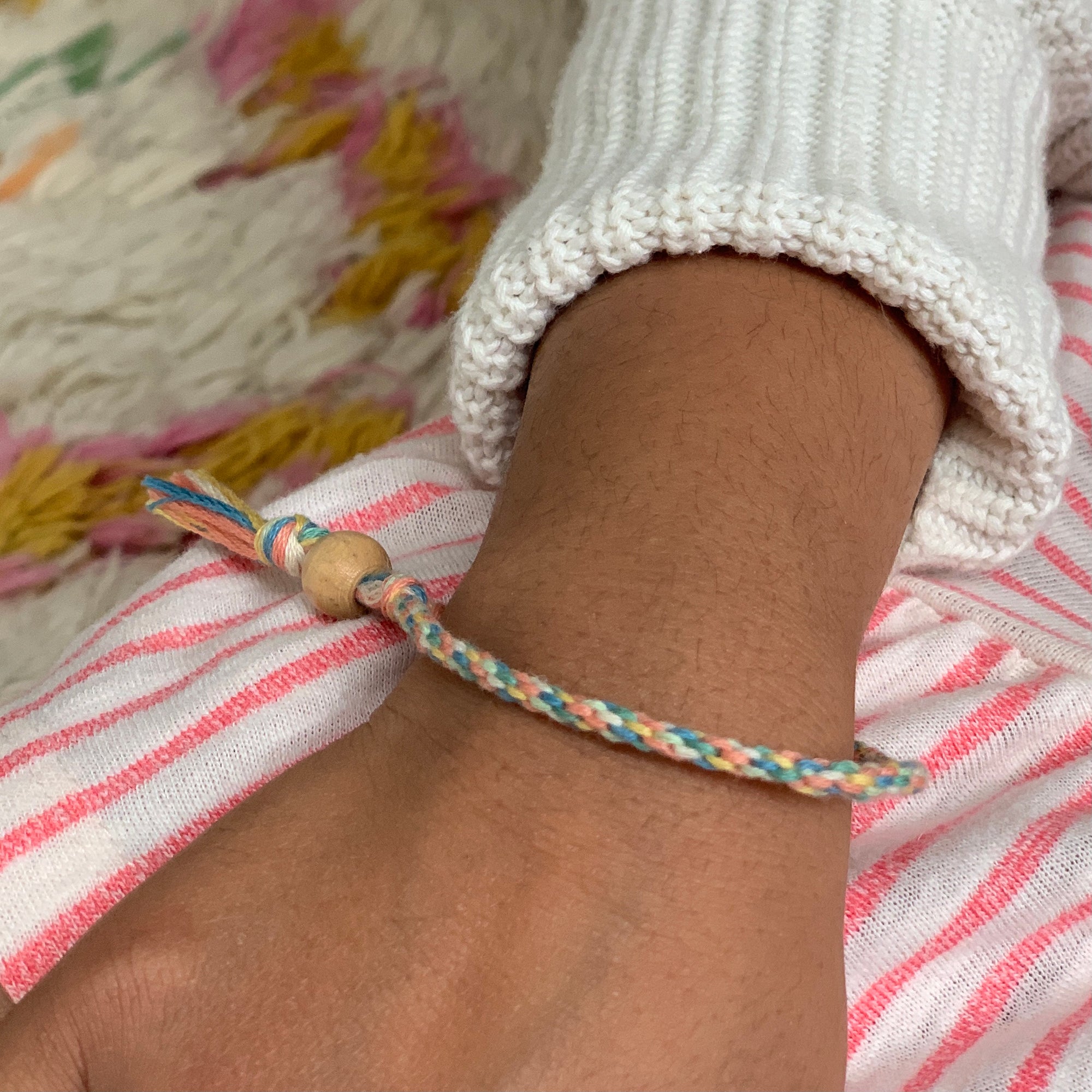 Finished friendship bracelets made from colourful threads and beads on child's arm