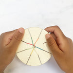 Child weaving a friendship bracelet using the wooden tool and colourful threads