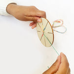 Child weaving a friendship bracelet using the wooden tool and colourful threads