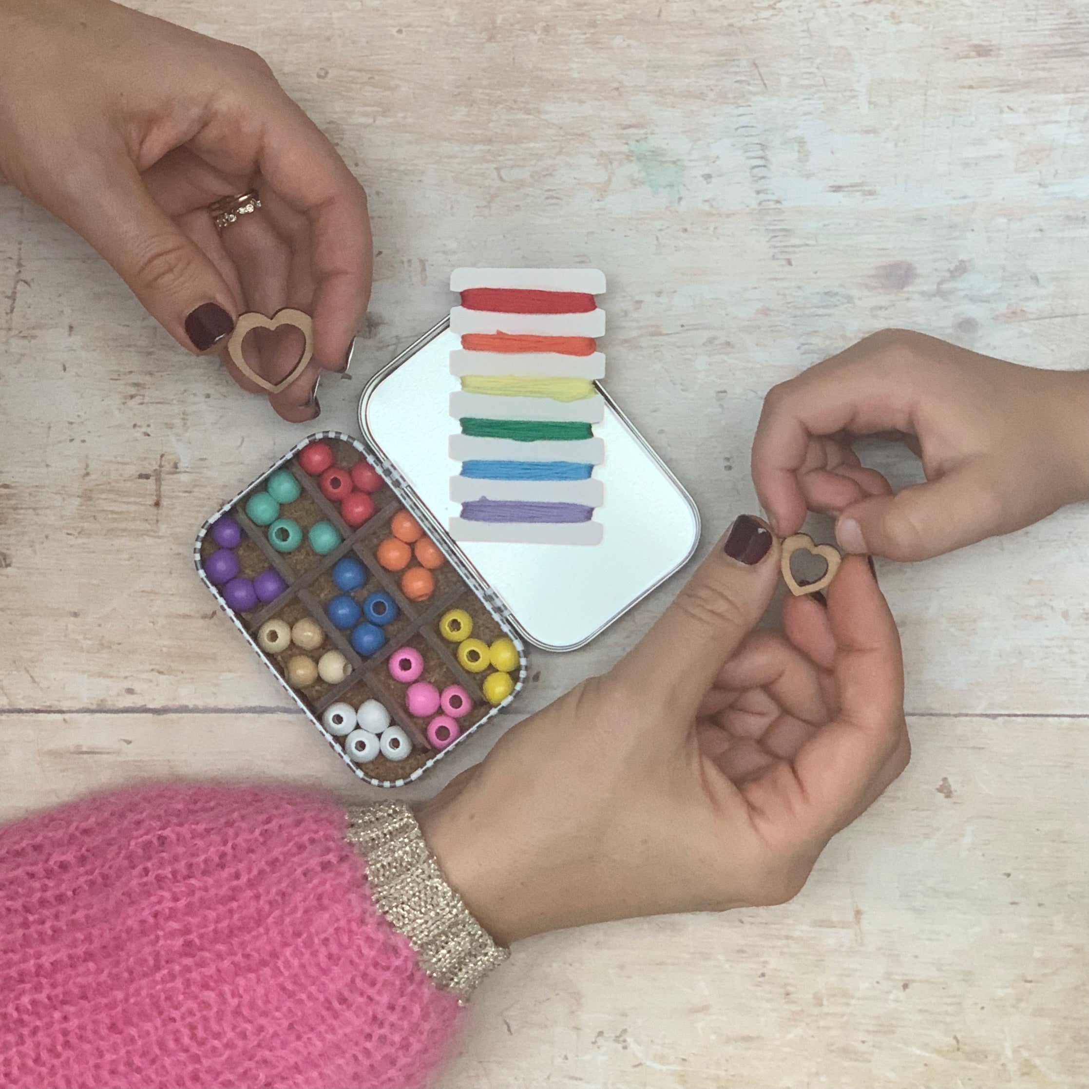 adult and child making a bracelet together