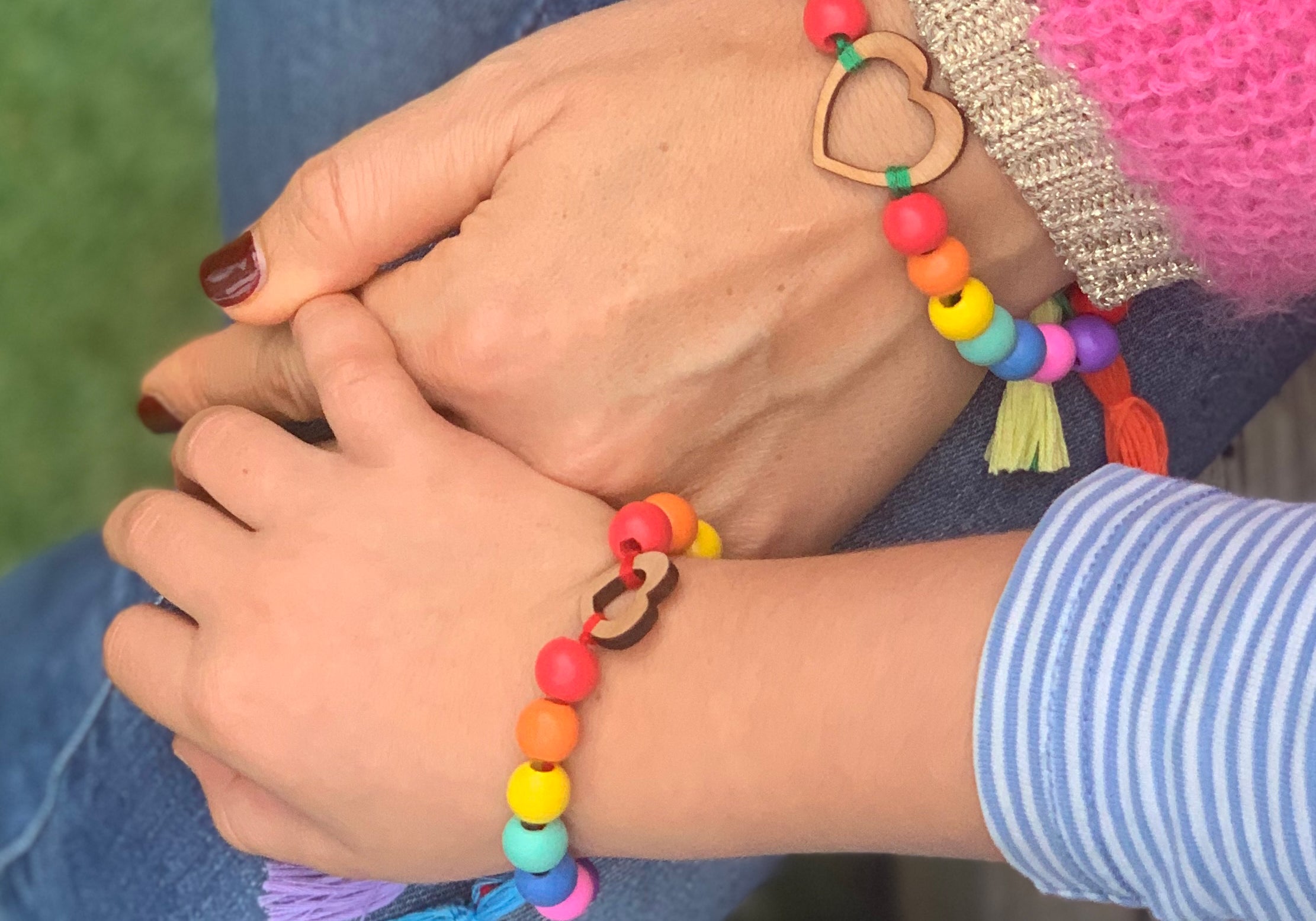 adult and child holding hands wearing bracelet