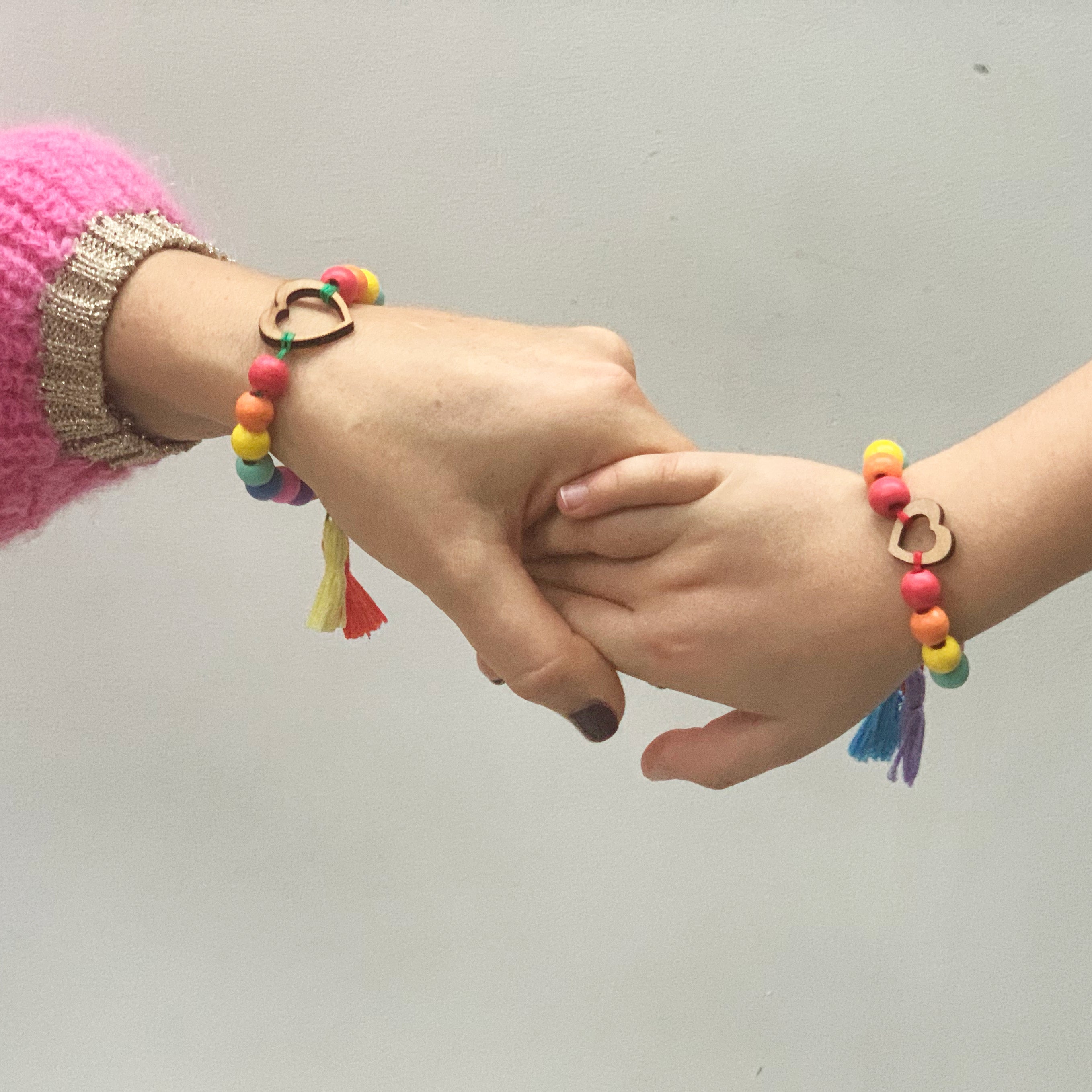 adult and child holding hands wearing bracelet